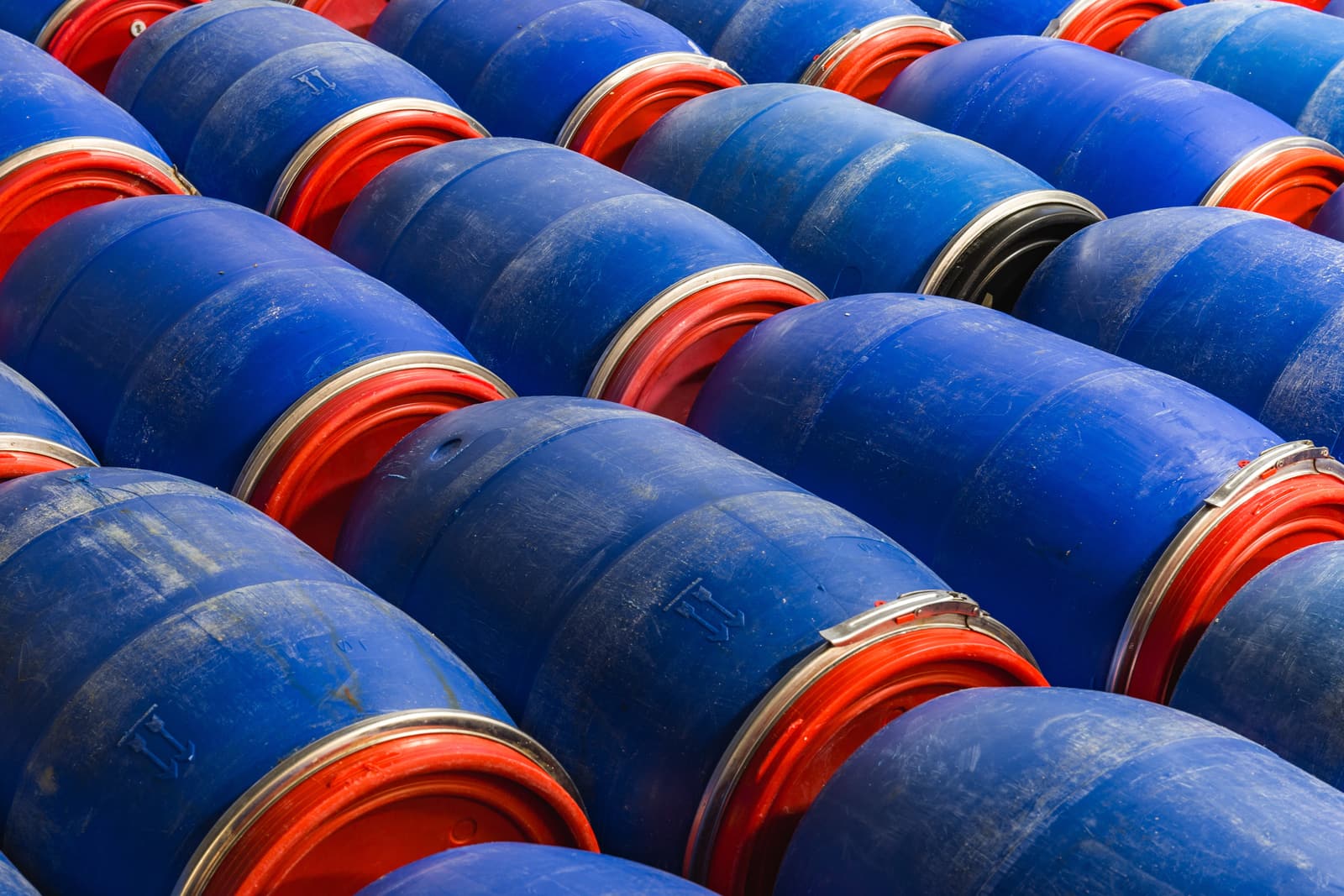 Rows of blue and red lubricant drums stacked in a warehouse